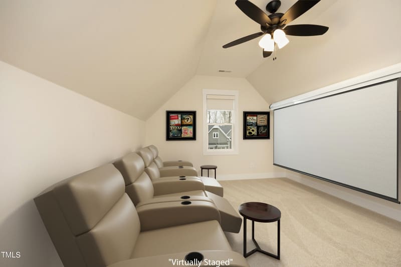 Home theater room with beige leather recliners, large projection screen, ceiling fan, movie posters, and sloped ceiling.